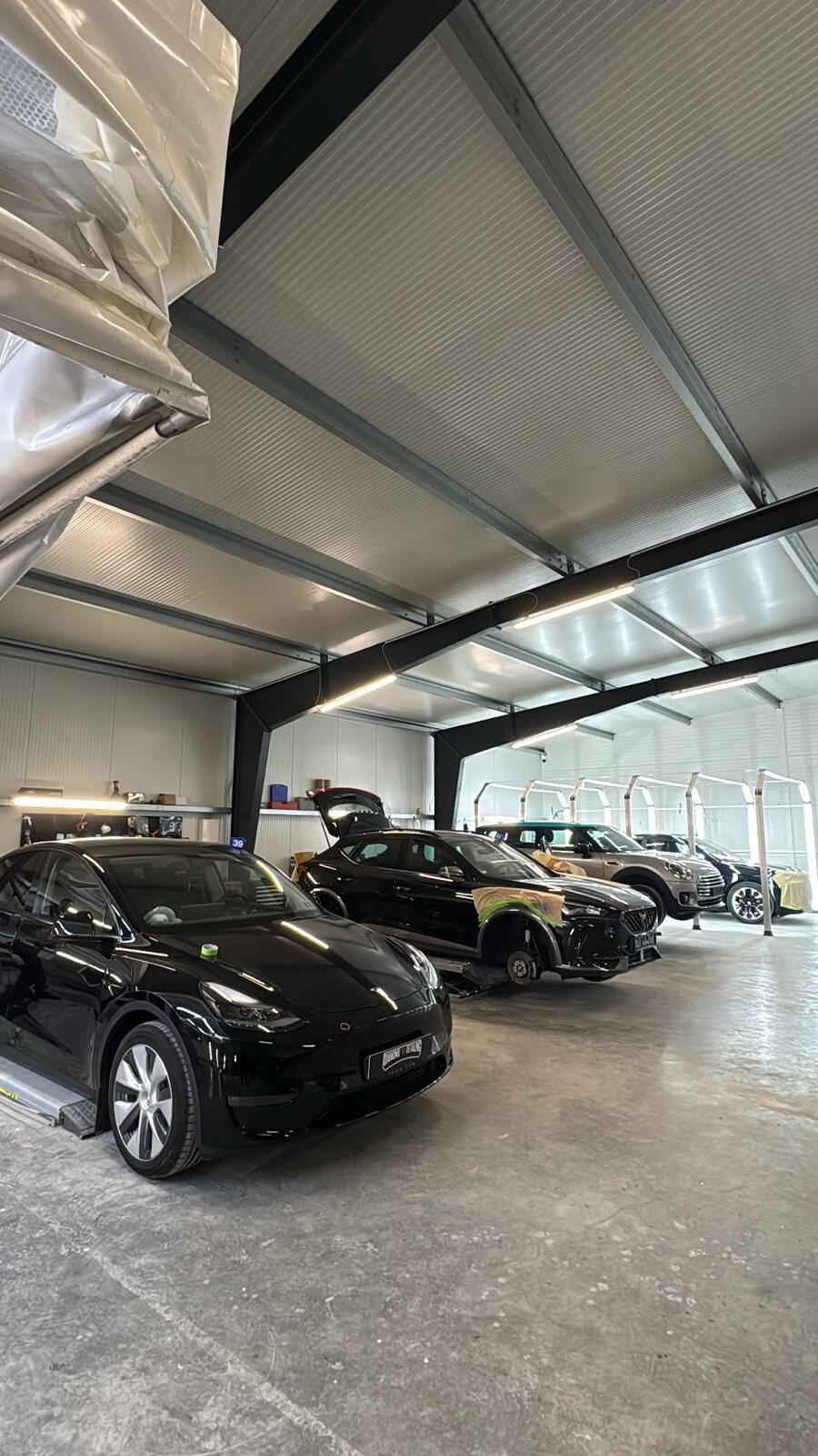 Die Halle von Diamond Detailing mit mehreren Fahrzeugen und dem Lichttunnel im Hintergrund